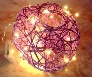 Photo of small purple acrylic yarn globe with warm colored faery lights