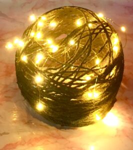 Photo of black and gold acrylic yarn globe with warm colored faery lights