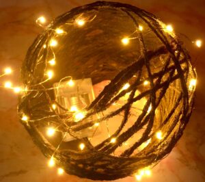 Up close aerial shot of small yarn globe light with warm colored faery lights